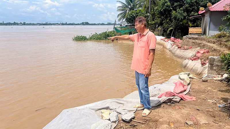 Ông Nguyễn Hoài Ơn chỉ tay về phía hiện trường vụ sạt lở. (Ảnh: HỮU NGHĨA)