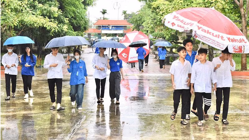 Lực lượng thanh niên tình nguyện giúp thí sinh vào địa điểm thi trong điều kiện trời mưa nặng hạt sáng 27/6.