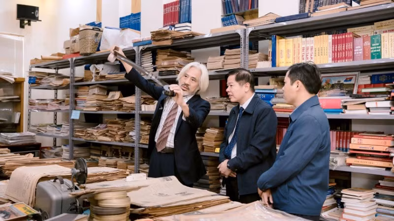 Ông Nguyễn Phi Dũng giới thiệu với khách tham quan những tờ báo giấy đã sưu tầm được.