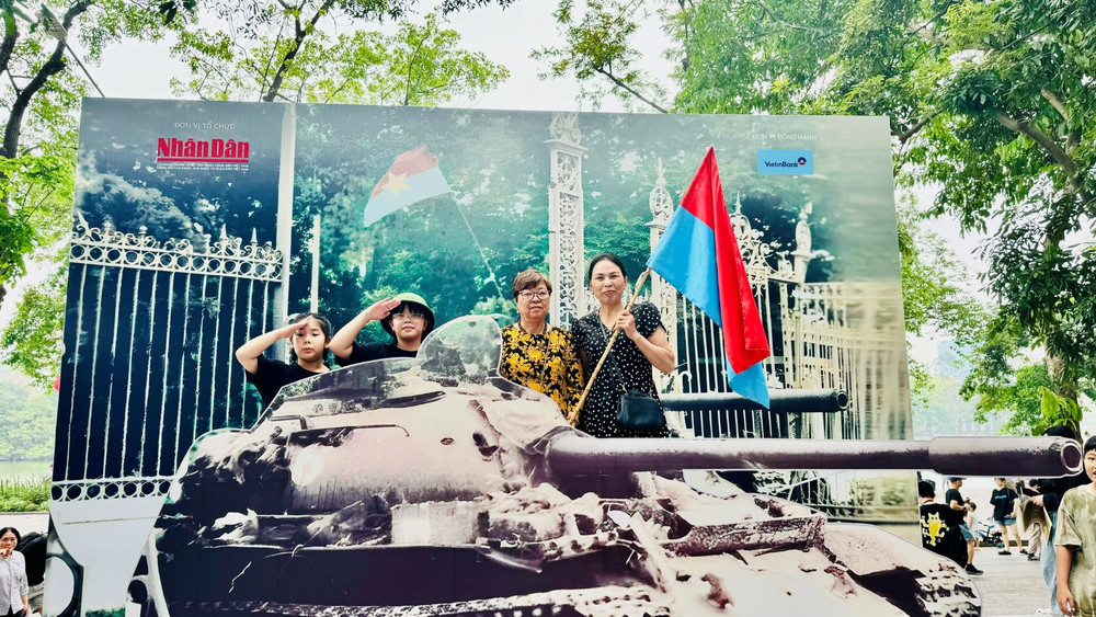 Bà Vương Thị Bình (cầm cờ) cùng người thân trong gia đình chụp ảnh tại mô hình xe tăng. (Ảnh: HNV) Bà Vương Thị Bình (cầm cờ) cùng người thân trong gia đình chụp ảnh tại mô hình xe tăng. (Ảnh: HNV)