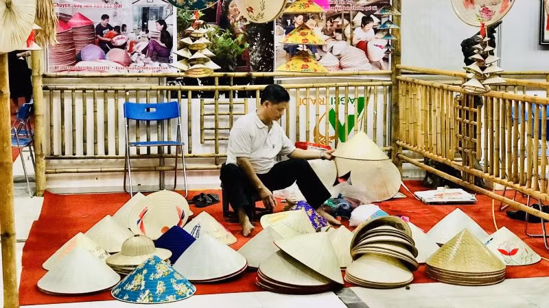 Nghệ nhân nghề nón là truyền thống trình diễn nghề trong một Hội chợ làng nghề. (Ảnh: HNV)