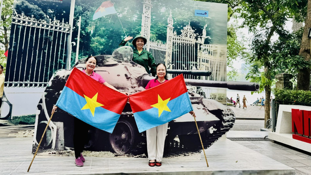 Bà Nguyễn Thị Tính, 71 tuổi (cầm cờ bên phải) chụp ảnh cùng các bạn mình tại triển lãm tương tác. (Ảnh: HNV) Bà Nguyễn Thị Tính, 71 tuổi (cầm cờ bên phải) chụp ảnh cùng các bạn mình tại triển lãm tương tác. (Ảnh: HNV)