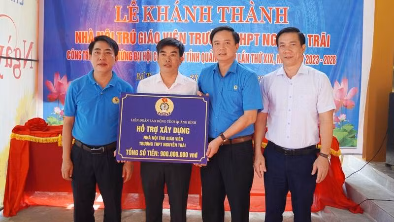 Chủ tịch Liên đoàn Lao động Quảng Bình Phạm Tiến Nam (áo xanh, giữa) trao kinh phí hỗ trợ xây nhà nội trú cho giáo viên ở huyện Bố Trạch.