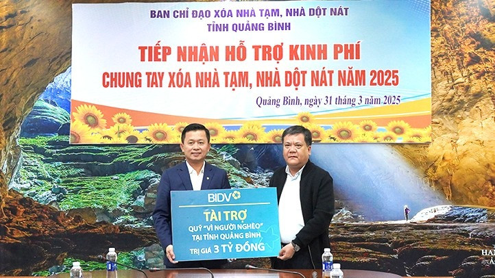 Chủ tịch Ủy ban nhân dân tỉnh Quảng Bình Trần Phong (bên phải) tiếp nhận hỗ trợ của BIDV để xóa nhà tạm, nhà dột nát cho hộ nghèo