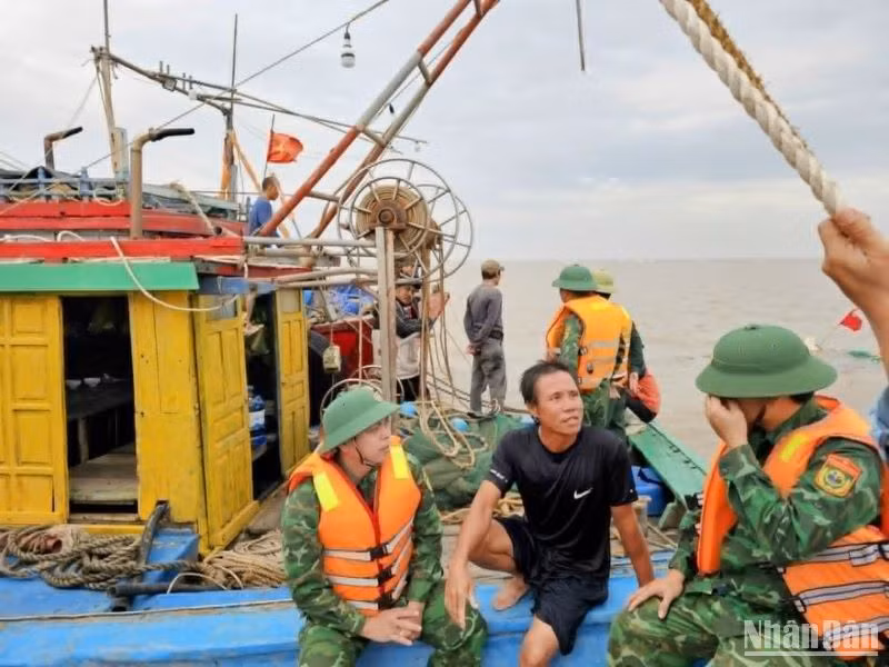 Ngư dân Tô Bá Chiến, người điều khiển tàu cá vỏ gỗ bị chìm (ngồi giữa) đang trao đổi với lực lượng biên phòng Cảng cửa khẩu Diêm Điền.