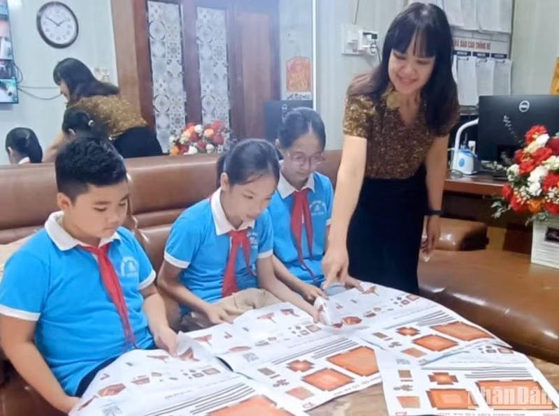 Cô trò trường Tiểu học thị trấn Vũ Thư (huyện Vũ Thư, tỉnh Thái Bình) tìm hiểu về ấn phẩm đặc biệt "Cột cờ Hà Nội" do Báo Nhân Dân trao tặng.