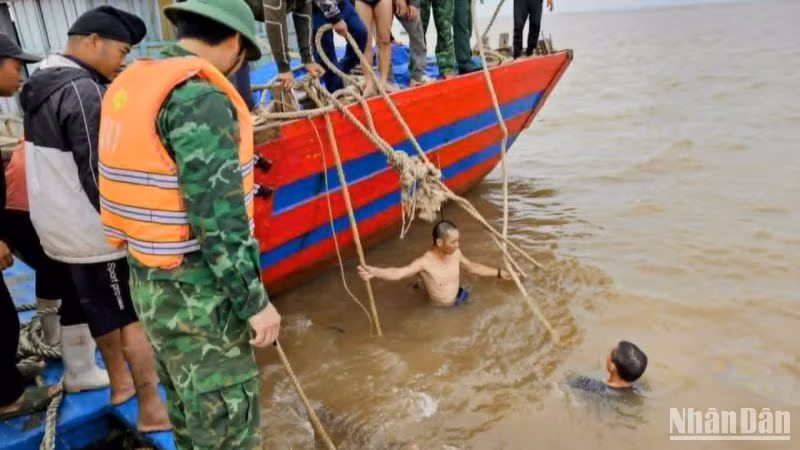 Huy động thợ lặn xuống nước buộc dây để lai dắt tàu cá bị chìm vào bờ.