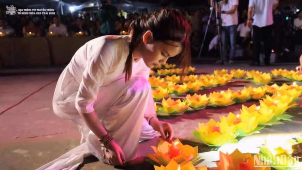 Một thiếu nữ trong tà áo dài đang nghiêm ngắn sắp xếp, chỉnh sửa những cánh hoa đăng.