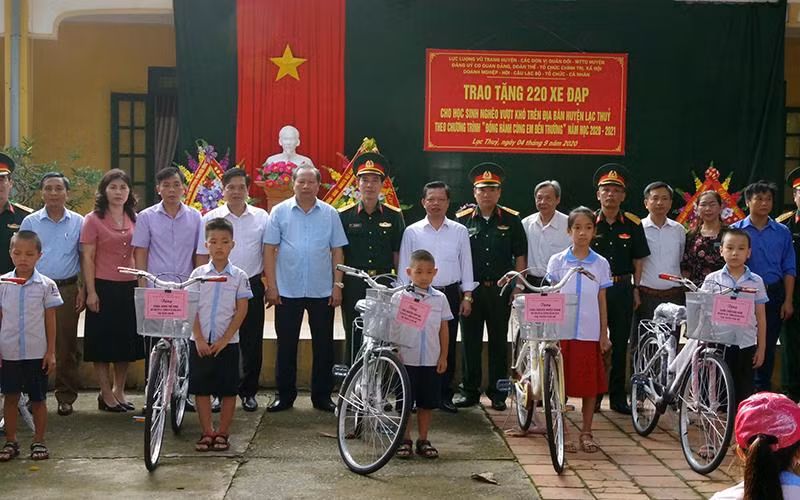 Ðại diện Bộ Chỉ huy quân sự tỉnh Hòa Bình cùng chính quyền địa phương trao xe đạp tặng học sinh nghèo huyện Lạc Thủy. 
