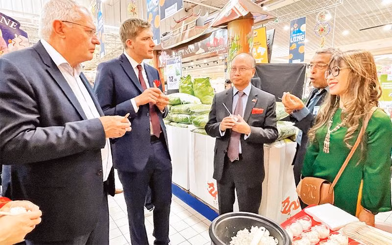 Các đại biểu nếm thử cơm Việt Nam tại siêu thị của Pháp. (Ảnh TTXVN) 