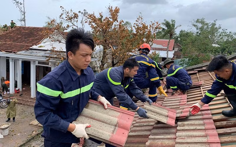 Lực lượng chức năng giúp dân lợp lại nhà bị tốc mái tại thôn Mai Vĩnh, xã Vinh Xuân, huyện Phú Vang, tỉnh Thừa Thiên Huế. (Ảnh CÔNG HẬU)