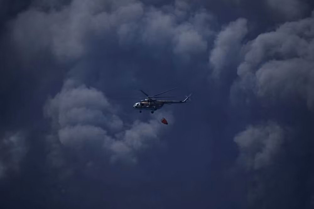 Một chiếc trực thăng chuẩn bị thả nước xuống kho dầu. (Ảnh: Reuters)