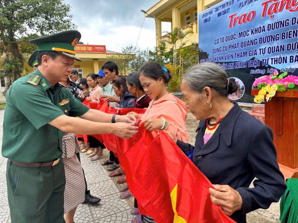 Trao tặng cờ Tổ quốc, móc khóa đường dây nóng cho bà con.