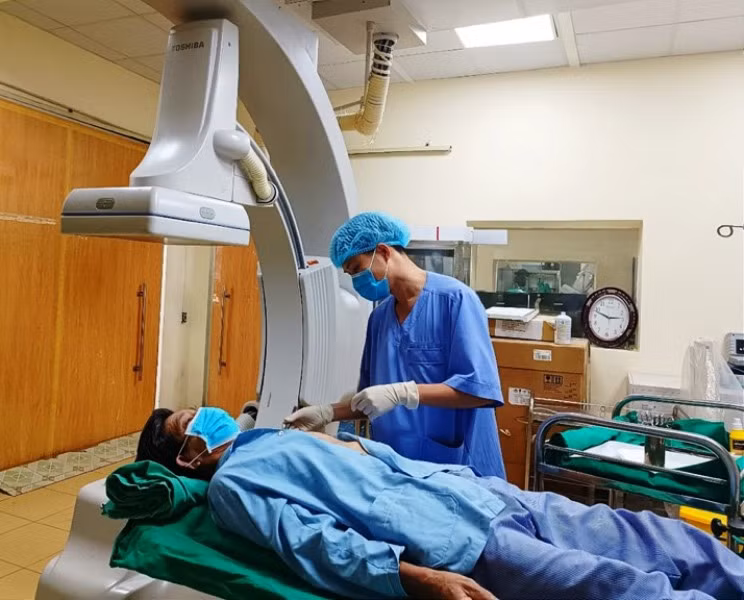 Nhân viên y tế sử dụng thiết bị hiện đại kiểm tra sức khỏe bệnh nhân sau can thiệp tim mạch.