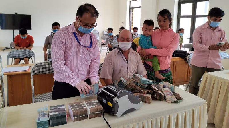 Cán bộ Ngân hàng Chính sách xã hội giúp bà con xếp gọn tiền trước khi gửi tiết kiệm tại Điểm giao dịch.