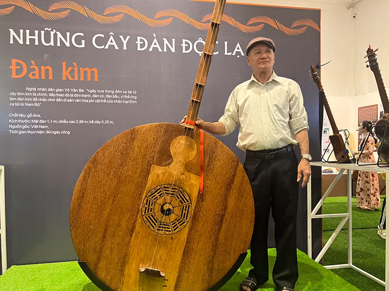 Nghệ nhân Võ Văn Bá bên cây đàn kìm bằng chất liệu gỗ dừa của mình.