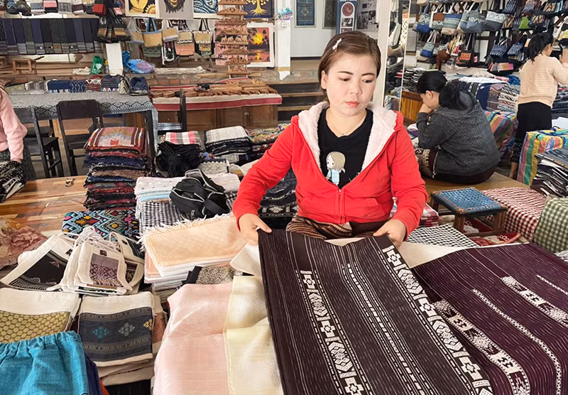Giới thiệu sản phẩm vải dệt thủ công của Lào cho du khách. (Ảnh: Hải Tiến)