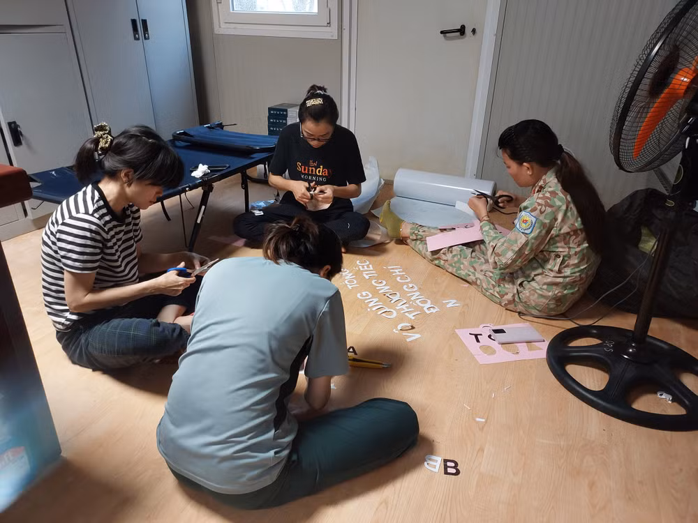 Tổ phụ nữ đang cắt giấy dán lên phông đen.