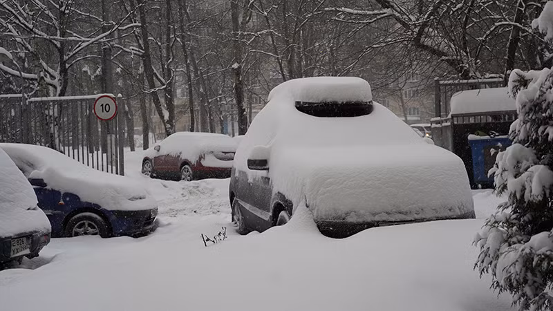 Chỉ trong thời gian ngắn, tuyết rơi đã phủ kín những chiếc ô tô đậu lề đường. (Ảnh: XUÂN HƯNG)