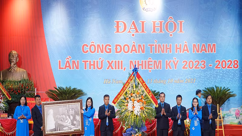 Đồng chí Nguyễn Đình Khang, Ủy viên Trung ương Đảng, Chủ tịch Tổng Liên đoàn Lao động Việt Nam tặng hoa chúc mừng và bức tranh "Bác Hồ với công nhân lao động Việt Nam" cho Đại hội.