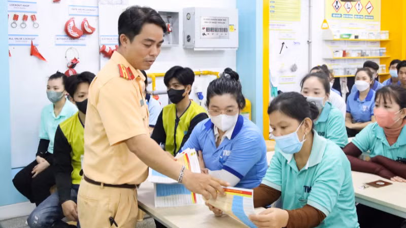 Cán bộ Phòng Cảnh sát giao thông, Công an thành phố phát tờ rơi tuyên truyền về những điểm mới của Nghị định 168/2024/NĐ-CP cho người lao động.