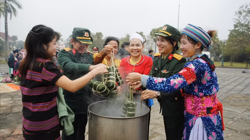 Đồng bào các dân tộc đang hoạt động tại "Làng" cùng các chiến sĩ tham gia luộc bánh chưng. (Ảnh: PH)