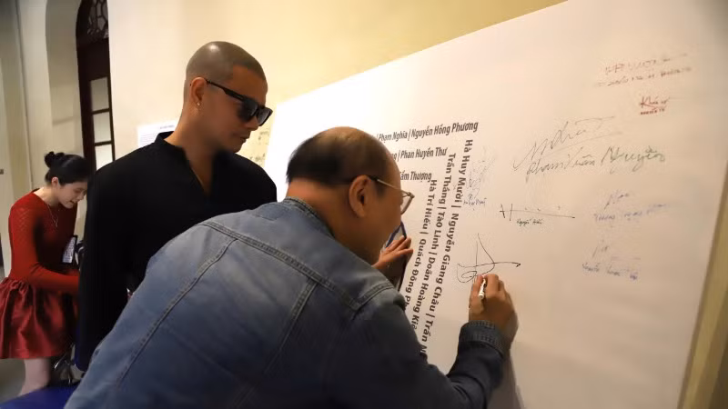 Các họa sĩ ký tên lưu niệm trong triển lãm.