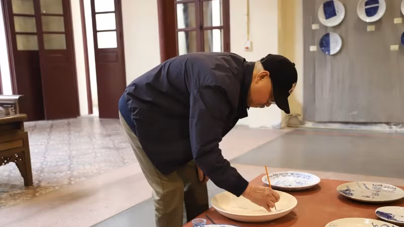 Công chúng yêu mến nhà văn ký tên trong đĩa gốm tại triển lãm.