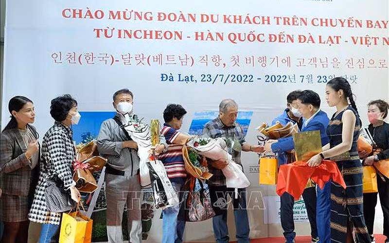 Đại diện Sở Văn hóa, Thể thao và Du lịch Lâm Đồng tặng hoa chúc mừng những du khách quốc tế đầu tiên đến Đà Lạt hôm 23/7. (Ảnh: TTXVN) 