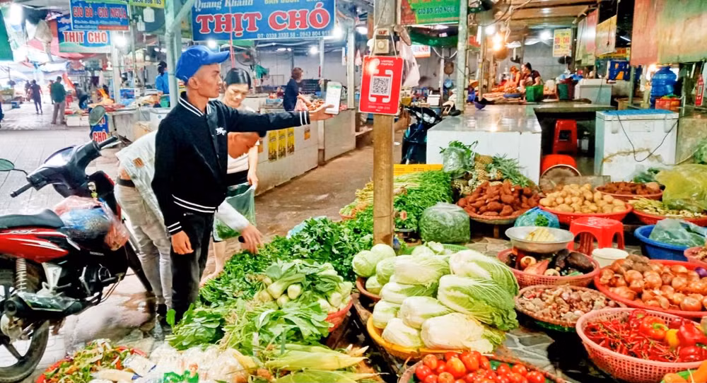 Người mua hàng tại chợ Đại Từ quét mã QR để thanh toán tiền.