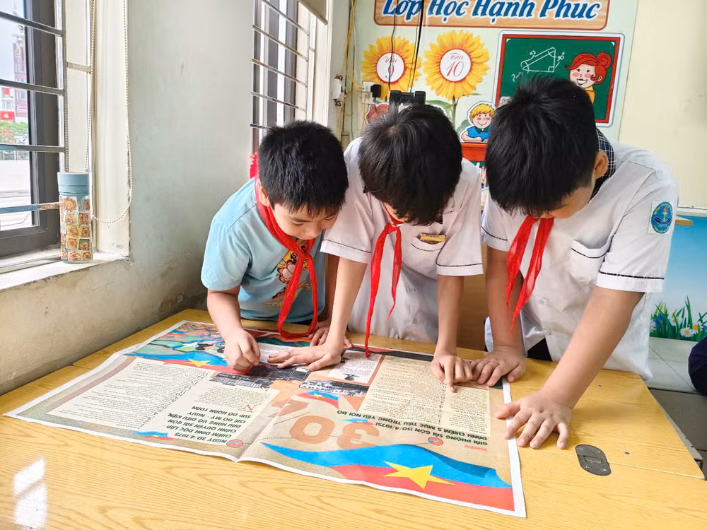 Các bạn nhỏ chăm chú tìm hiểu lịch sử qua những trang Báo in màu đặc sắc.