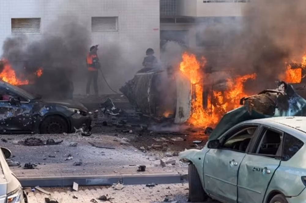 Người dân dập các đám cháy trên xe ô-tô sau vụ tấn công bằng rocket từ Dải Gaza tại Ashkelon (Israel), ngày 7/10/2023. (Ảnh: AFP/TTXVN)