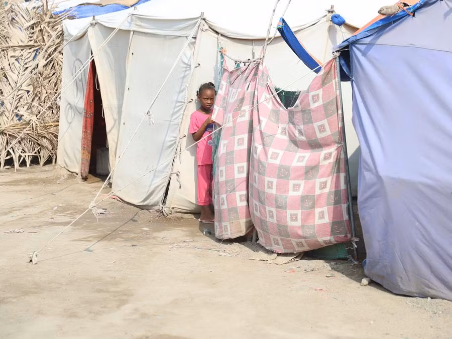 Một bé gái đứng cạnh một chiếc lều tại một trung tâm dành cho những người phải di dời ở Port Sudan, miền đông Sudan. Ảnh: Tân Hoa xã