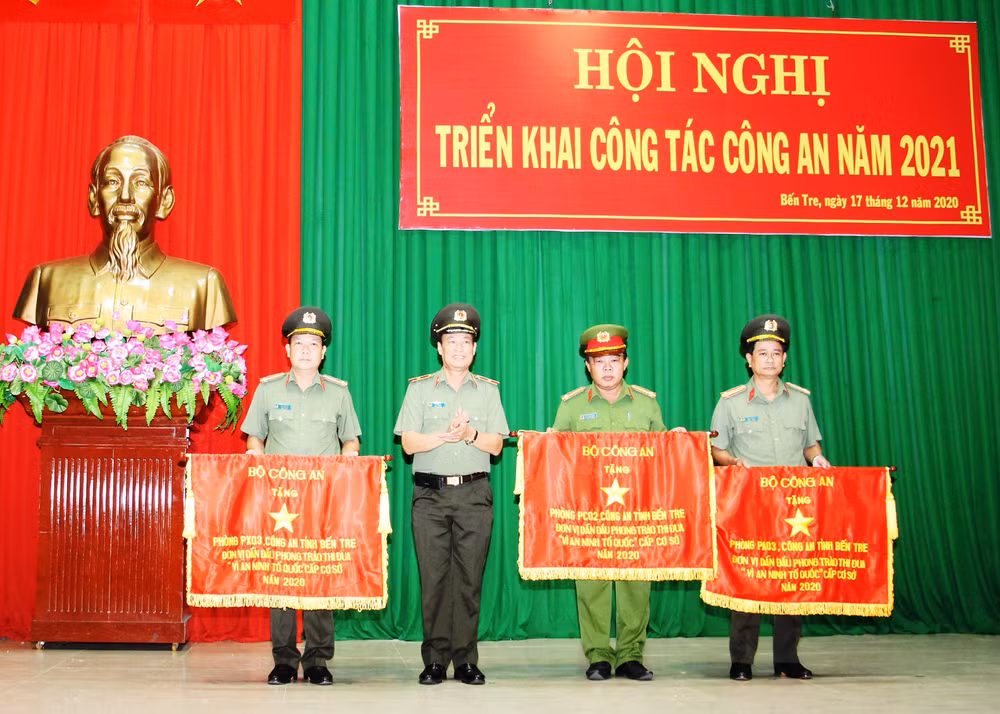 Đồng chí Trương Tấn Tùng (bìa phải) nhận cờ của Bộ Công an tặng đơn vị dẫn đầu phong trào thi đua “Vì an ninh Tổ quốc” cấp cơ sở năm 2020.