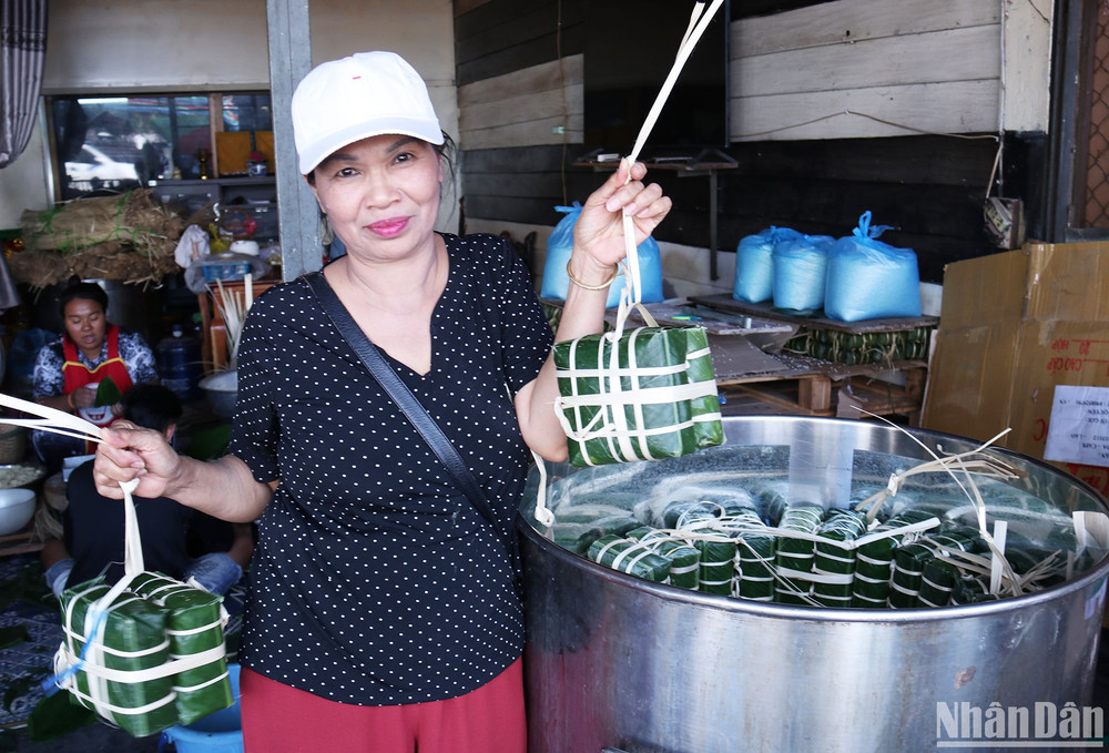 Cô Mai, người có thể gói 200 chiếc bánh chưng trong một buổi sáng, hào hứng khoe mẻ bánh đang được xếp vào nồi. (Ảnh: TRỊNH DŨNG)