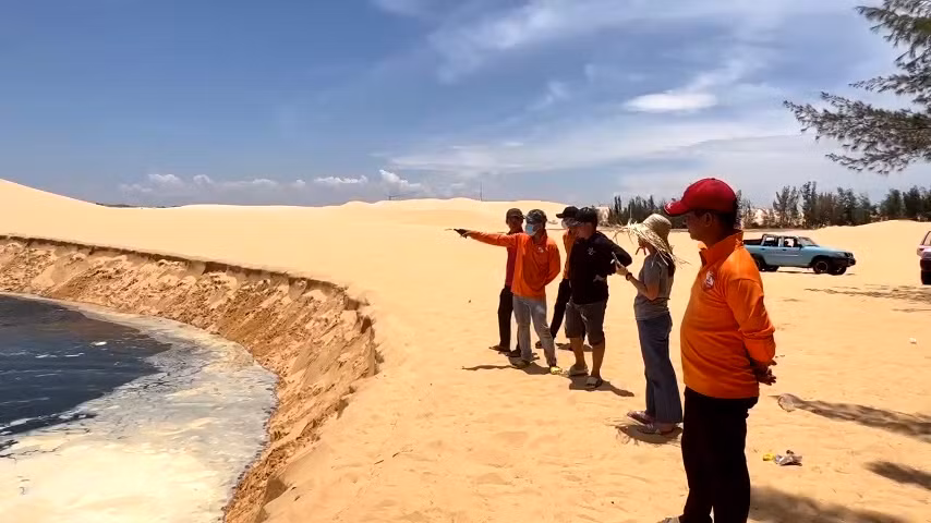 Người dân và du khách theo dõi hiện tượng sạt lở cát tại điểm du lịch Bàu Trắng.