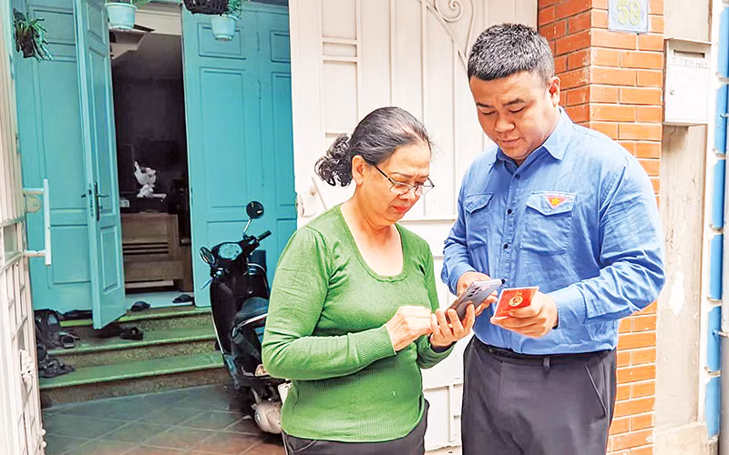Đoàn viên thanh niên phường Thụy Khuê (Tây Hồ) hướng dẫn sử dụng ứng dụng “Sổ tay đảng viên điện tử Thành ủy Hà Nội”. (Ảnh VIẾT TUẤN)