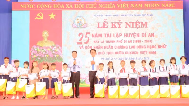 Lãnh đạo Hội đồng nhân dân tỉnh và lãnh đạo Ban Dân vận Tỉnh ủy Bình Dương trao học bổng và quà cho học sinh có hoàn cảnh khó khăn.