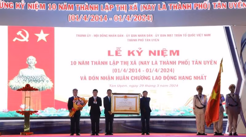 Thừa ủy nhiệm, Chủ tịch Ủy ban nhân dân tỉnh Bình Dương Võ Văn Minh (thứ 2 từ trái sang) trao Huân chương Lao động hạng Nhất cho lãnh đạo thành phố Tân Uyên. 