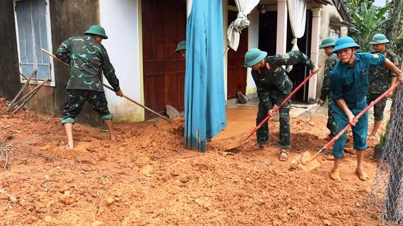 Các lực lượng giúp dân dọn bùn, đất đá tràn vào nhà do sạt lở núi tại huyện Phú Lộc.