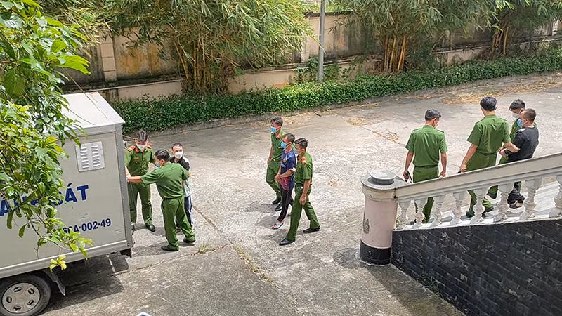 Lực lượng Công an đưa các bị cáo ra xe. (Ảnh: HỮU NGHĨA)