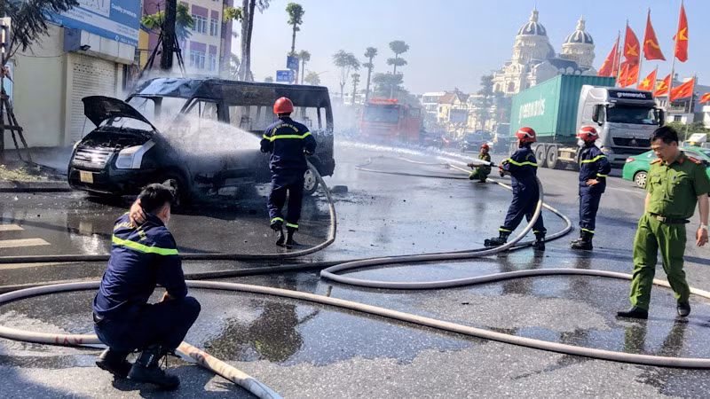 Lực lượng chữa cháy nỗ lực dập tắt đám cháy xe ô-tô trên đường.