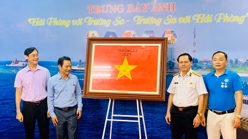 Chuẩn đô đốc Phạm Văn Luyện, Phó chủ nhiệm Chính trị Quân chủng Hải quân và nhà nhiếp ảnh Đỗ Trọng Luân trao cờ Tổ quốc có nhiều chữ ký của lãnh đạo các đảo ở Trường Sa và Nhà giàn DK tặng Hội Nhà báo thành phố Hải Phòng.