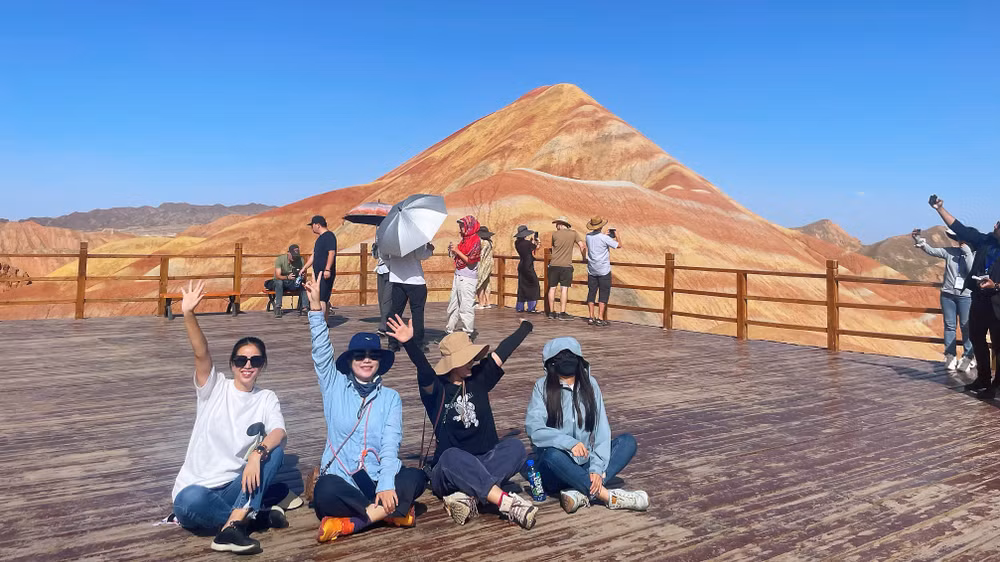 Du khách check-in bên khung cảnh núi đồi rực rỡ sắc màu. (Ảnh: HỮU HƯNG)