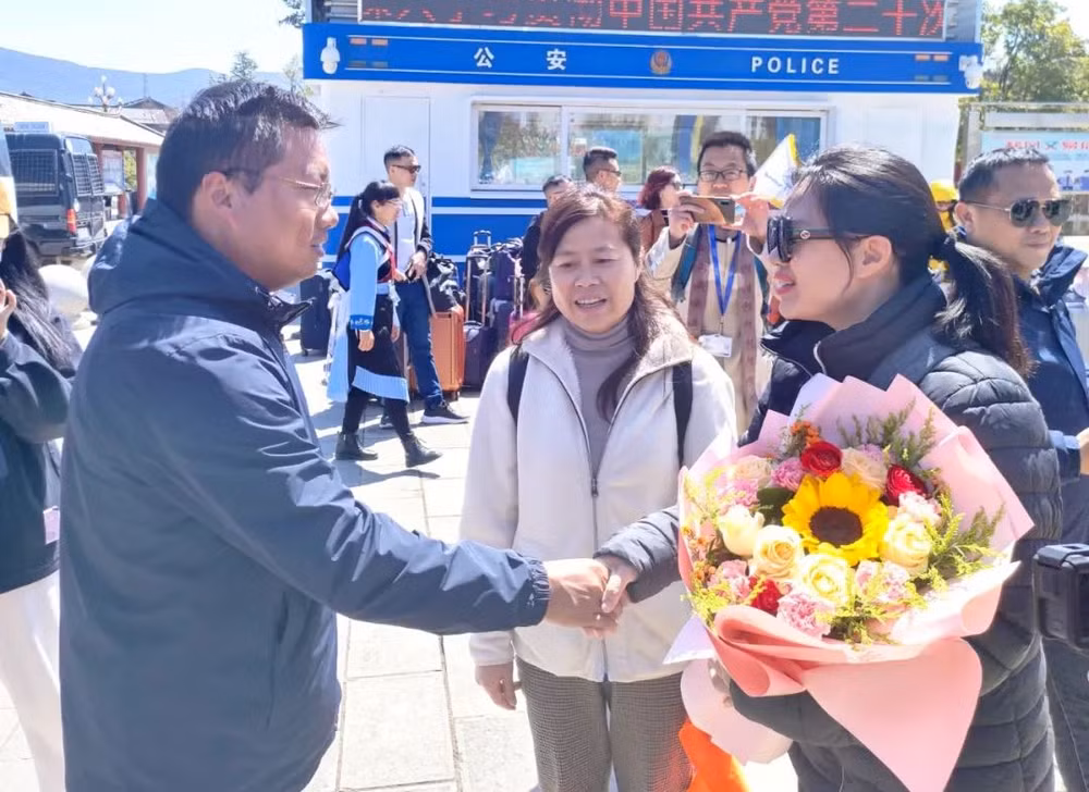 Đại diện thành phố Lệ Giang tặng hoa du khách Việt Nam. (Ảnh: Lijiang.cn)