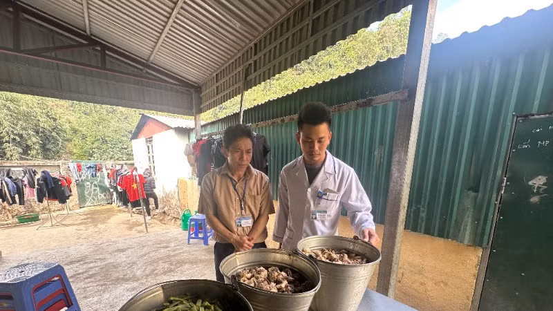 Cán bộ y tế xã Mường Pồn cùng thầy Nguyễn Văn Tới, Hiệu trưởng Trường Trung học cơ sở Mường Pồn kiểm tra thực phẩm đã chế biến trước khi cho học sinh ăn trưa ở trường.