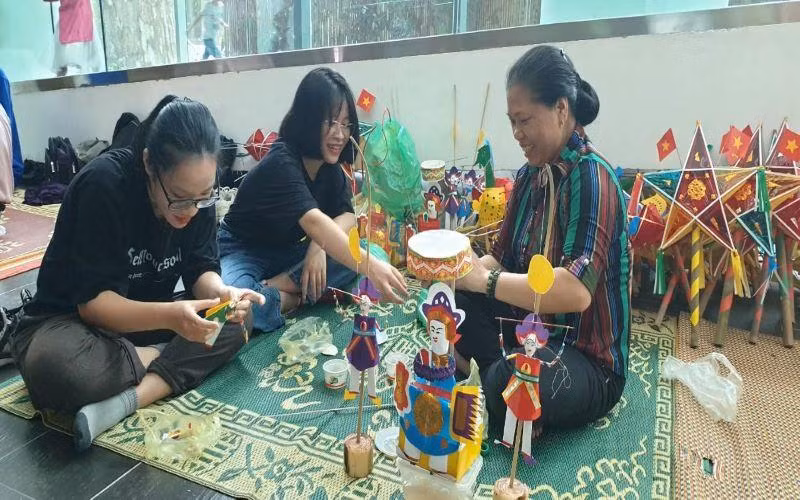 Nghệ nhân Nguyễn Thị Tuyến đang hướng dẫn cách làm đồ chơi trung thu cho du khách.