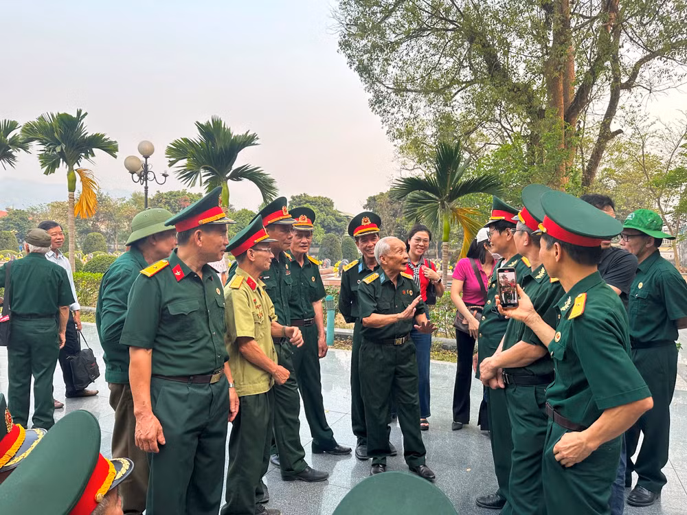 Trong khuôn viên Nghĩa trang Liệt sĩ Điện Biên Phủ, ông Dương Chí Kỳ (người ở giữa) đang kể chuyện đào hào trên đồi A1.