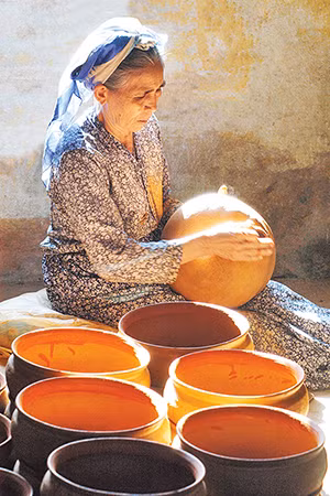 Nghệ nhân Ưu tú Đơn Thị Hiệu, làng gốm Chăm Bình Đức đang tạo hình một sản phẩm gốm. (Ảnh: Ngọc Lân)