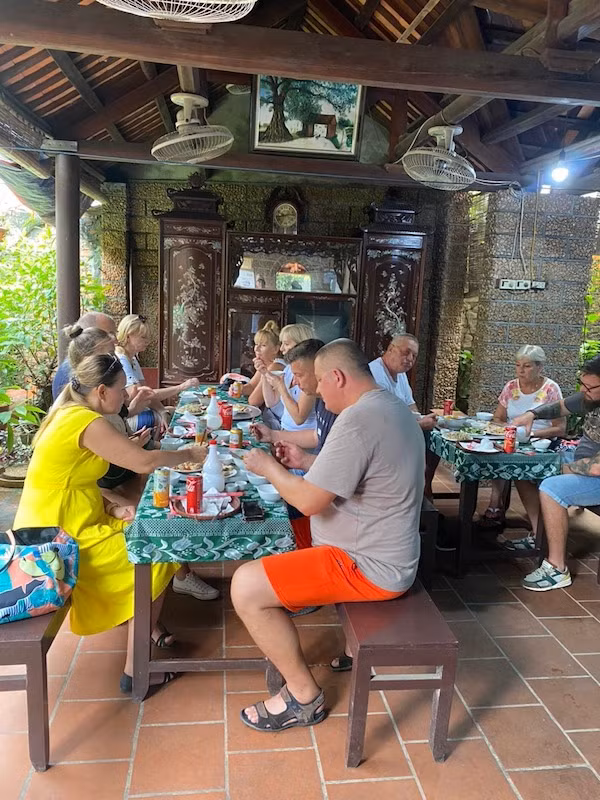 Khách du lịch nước ngoài thưởng thức ẩm thực truyền thống trong không gian nhà cổ tại Làng cổ Đường Lâm. (Ảnh: Trọng An)